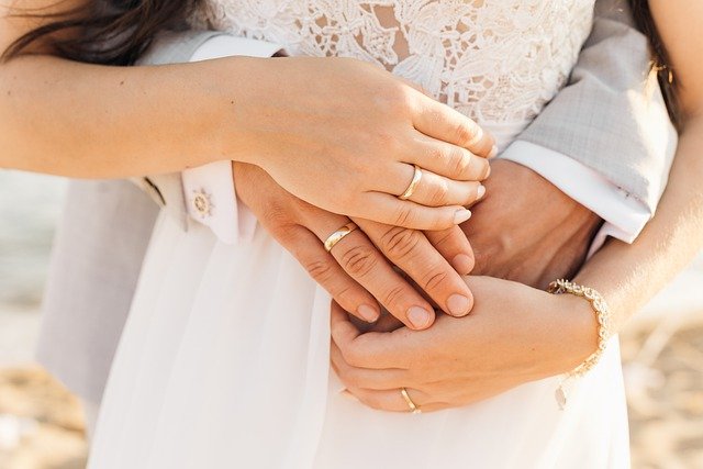 男女が結婚指輪をつけている手元の画像