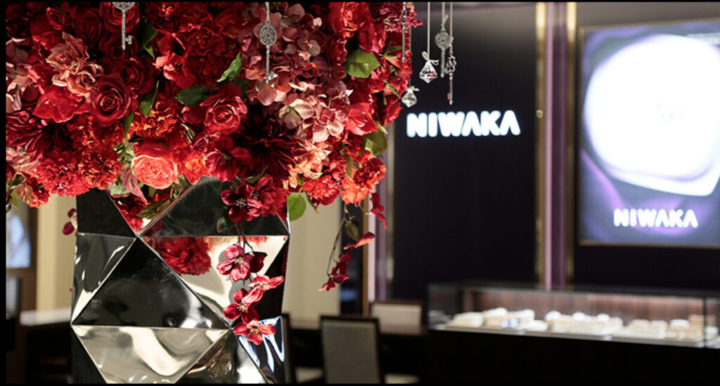 一真堂桜木インター店の店内の様子。赤く大きな花のオブジェとNIWAKAの
専用サロンの画像。