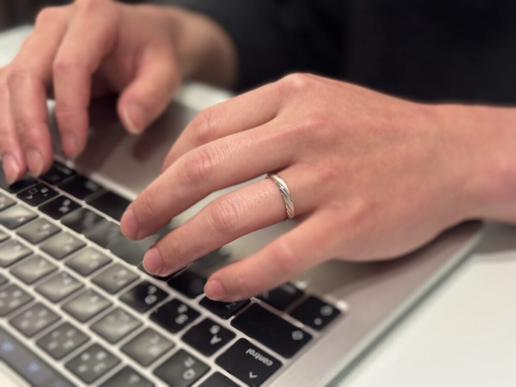 仕事中に結婚指輪をつけている男性の手元
