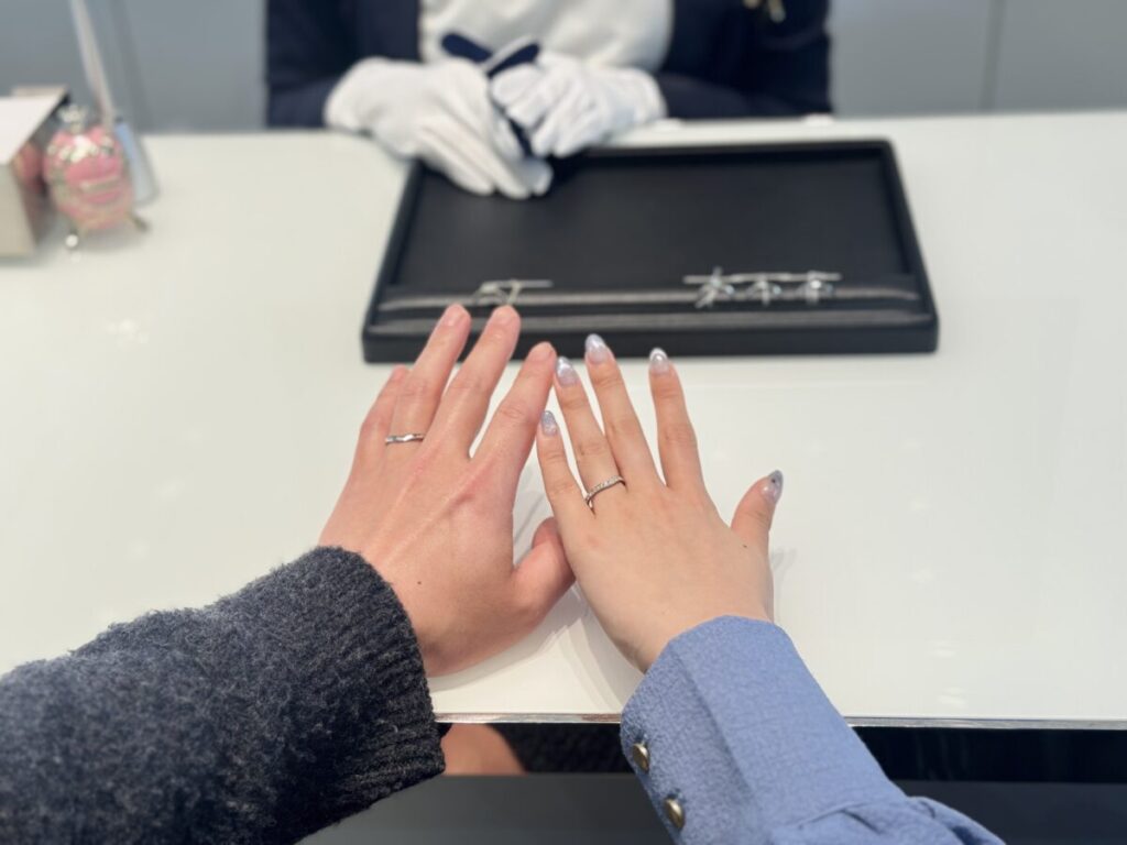ショップで結婚指輪を試着するカップルの手元