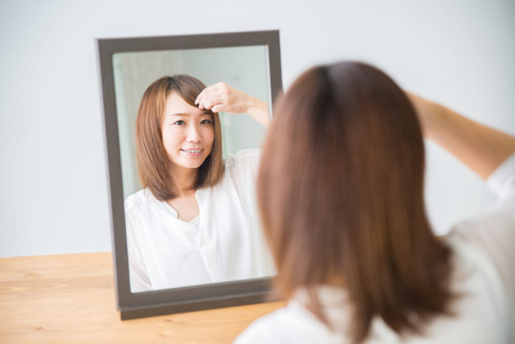 鏡で髪形をチェックする女性