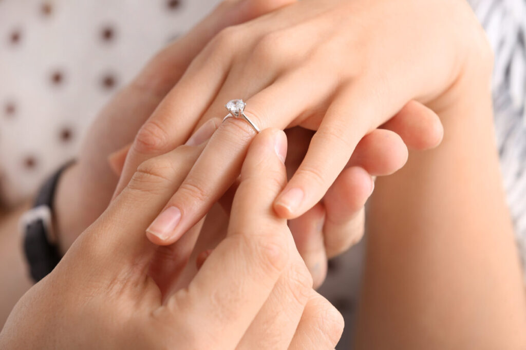 女性の薬指に婚約指輪をはめる男性