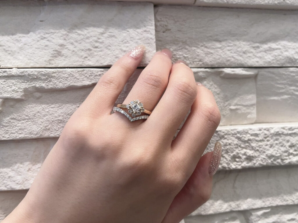 ハワイアンジュエリーの婚約指輪とV字のエタニティリングを重ねづけした手元の画像