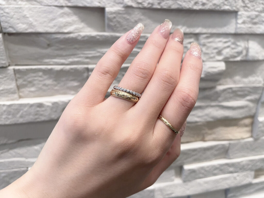 ハワイアンジュエリーとダイヤモンドのエタニティリングを重ねづけした手元の画像