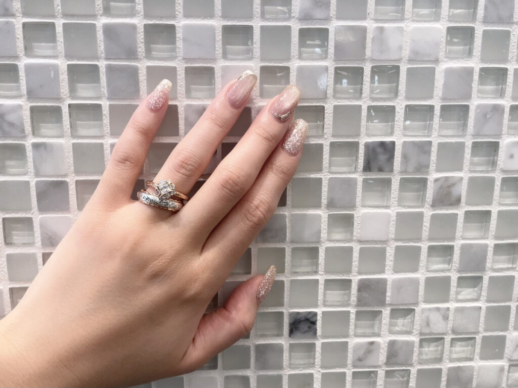 ピンクゴールドとホワイトゴールドのハワイアンジュエリーのリングを重ねづけした手元の画像。