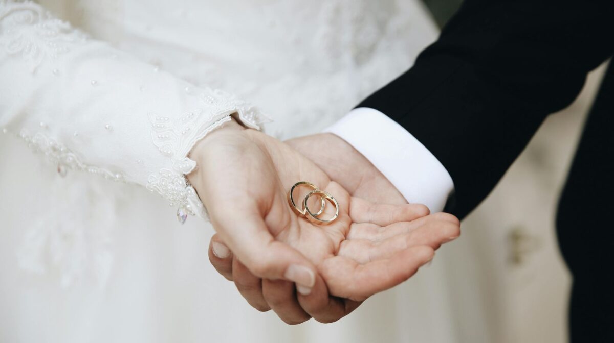 結婚指輪を手に乗せるカップル