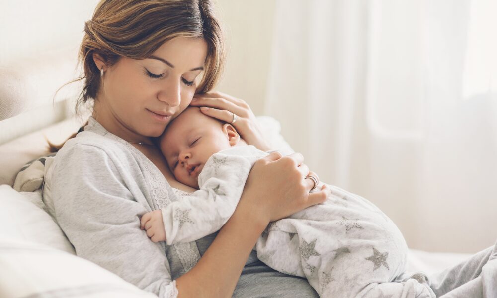 寝ている赤ちゃんを抱っこする女性