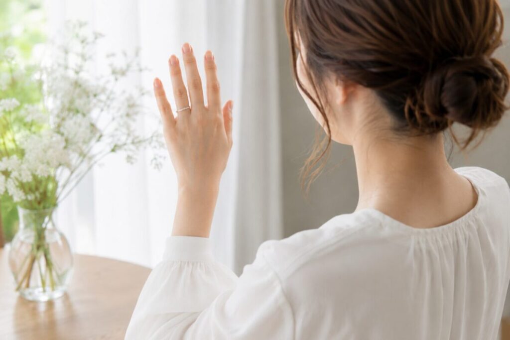 結婚指輪を着けた手元を見つめる女性