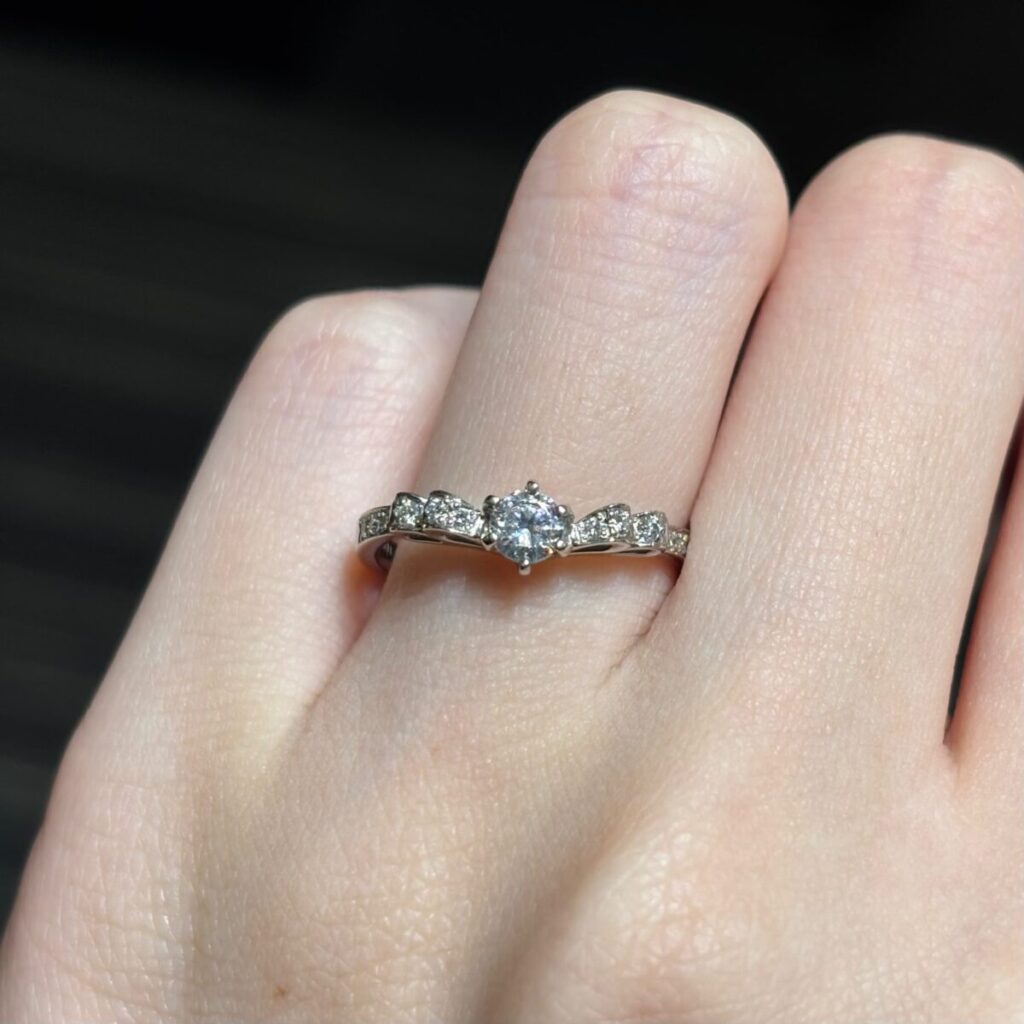 V字のリボンモチーフの婚約指輪をつけた手元